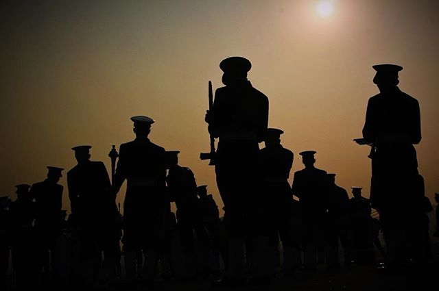 Silhouetted soldiers stand in formation against a sunset sky, embodying strength and duty.