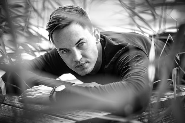 A black and white close-up shows a man lying in grass, wearing a watch.