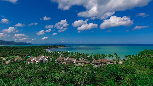An aerial view of a tropical beach resort with palm trees, ocean and blue sky for travel and vacation planning.