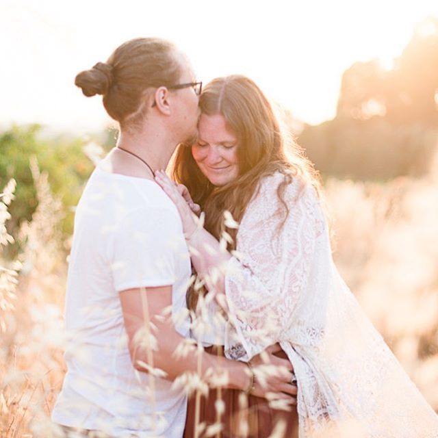 A loving couple embraces in a sunlit field, showcasing a tender and intimate moment.