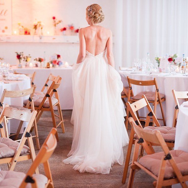 A bride in a wedding dress walks through a reception venue, creating an elegant and dreamy atmosphere.