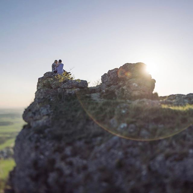 A couple embraces on a mountain peak, silhouetted by the sun, perfect for adventure or romance concepts.