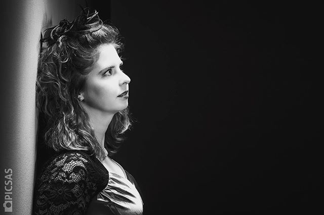 Elegant woman in vintage style strikes a contemplative pose in a classic black and white portrait.