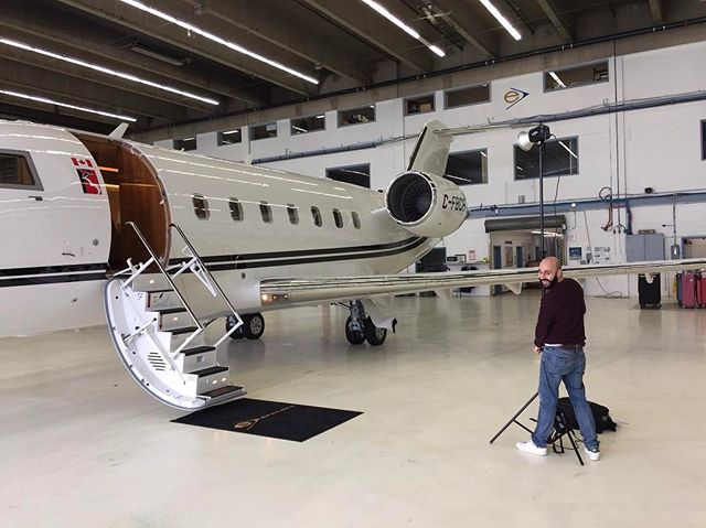 A man stands near a private jet in an airport hangar, capturing a moment of luxury and convenience.