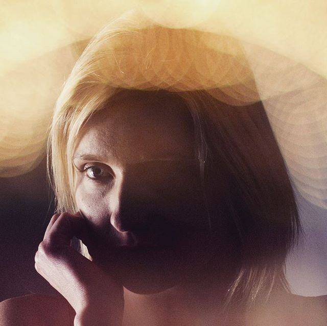 A woman with blonde hair poses softly, with bokeh lights creating a dreamy atmosphere.