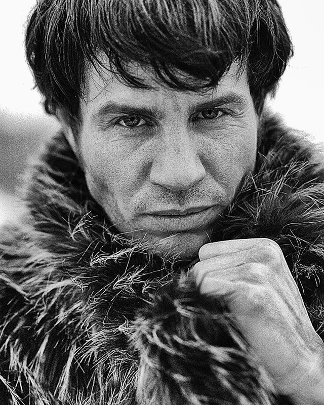 A dramatic monochrome portrait of a man in a fur coat, conveying intensity and power.