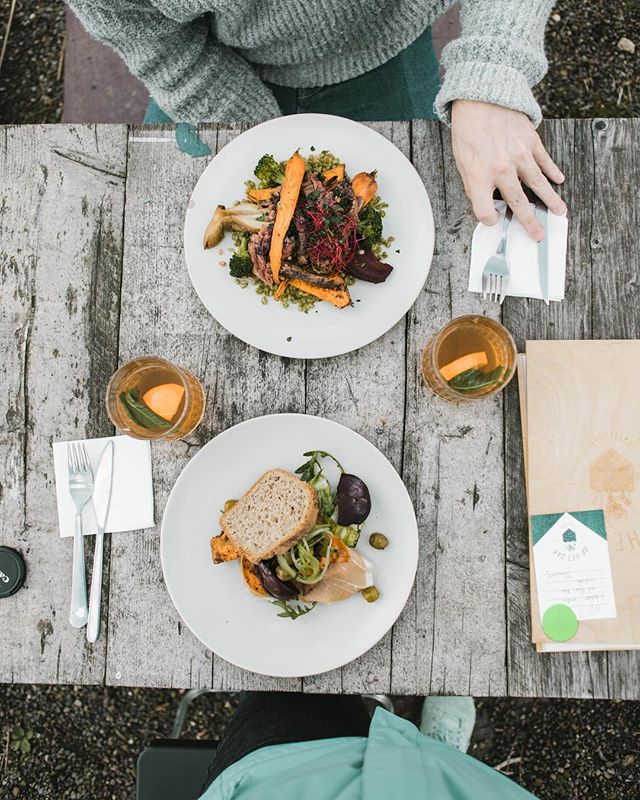 Overhead shot of two plates of food and drinks on a rustic wooden table, suggesting a dining experience.