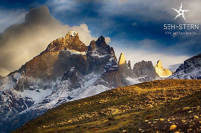 Scenic view of snow-capped mountains under a partly cloudy sky, capturing the rugged beauty of Patagonia.