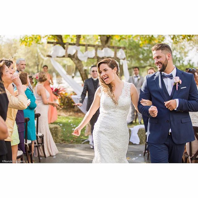 A happy bride and groom walk down the aisle after their wedding ceremony, surrounded by cheering guests.