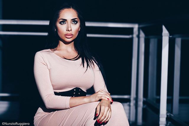 An elegant woman in a dress poses in a studio, showcasing modern fashion and confident style.