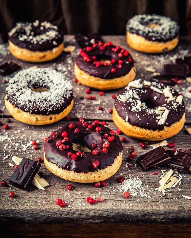 Delicious chocolate-covered donuts with colorful sprinkles arranged on a rustic wooden surface.