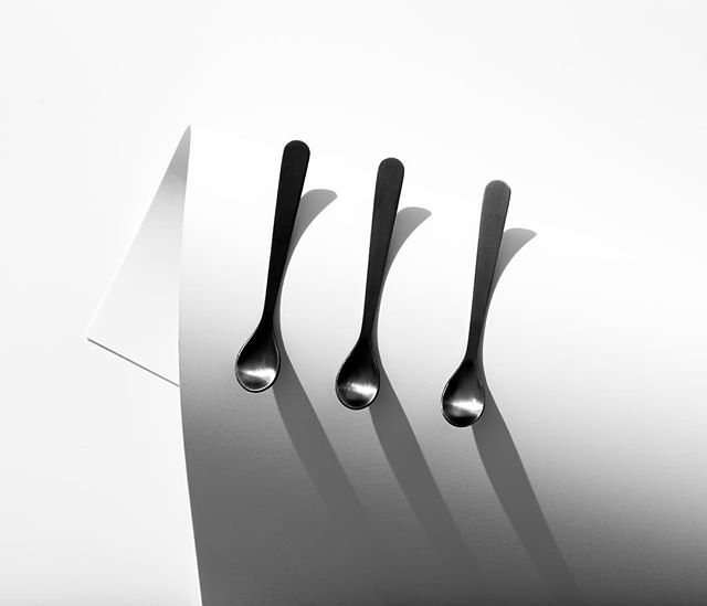 Three small spoons are arranged on a white surface in a minimalist composition.