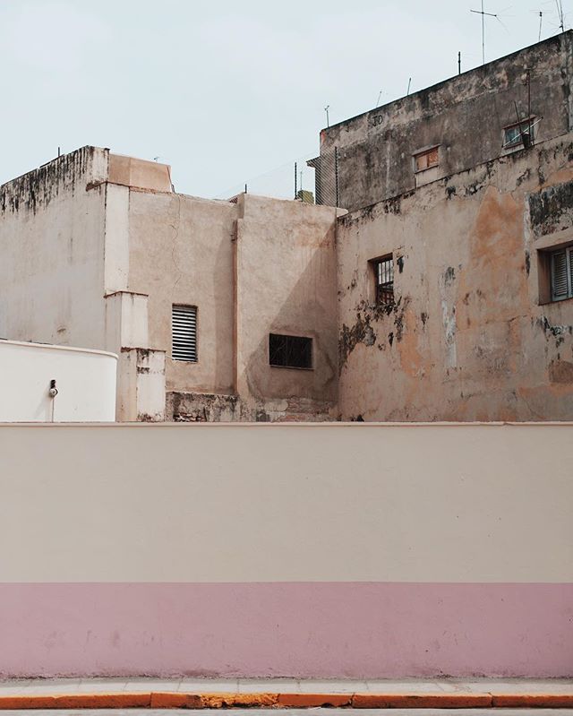 Urban scene featuring buildings and a wall with pink trim, creating a minimalist aesthetic.