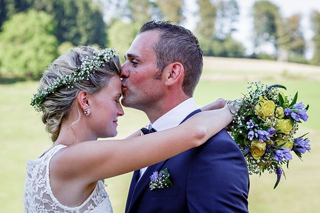 A bride and groom share an intimate moment on their wedding day in a natural outdoor setting.