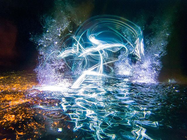 Abstract light painting creates a mesmerizing and dreamy effect over water at night.
