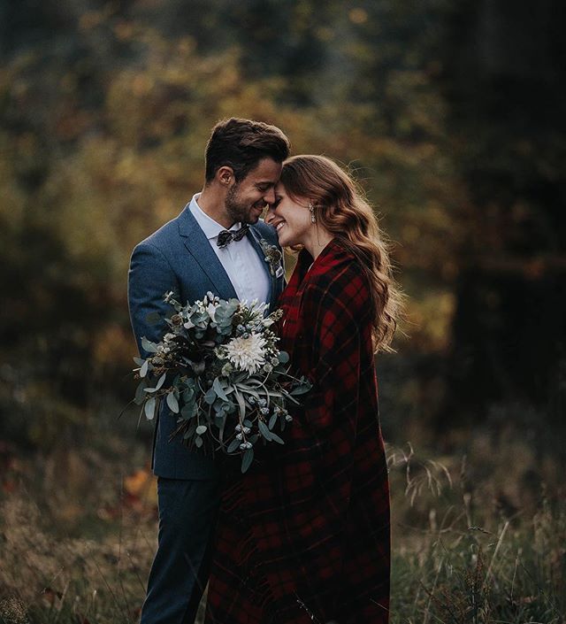 A loving couple embraces outdoors with a bouquet, radiating warmth and romance.