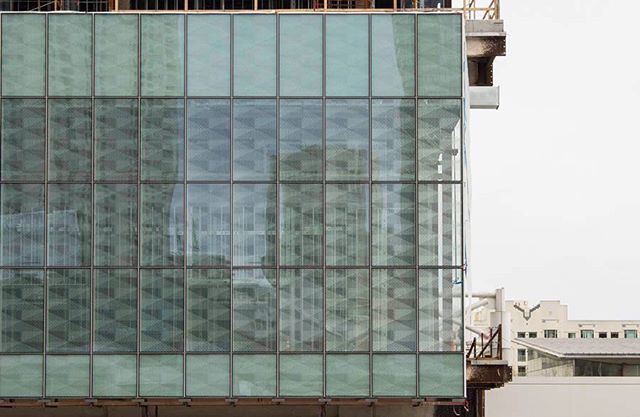 Modern building facade featuring glass panels, reflecting a tranquil urban landscape.