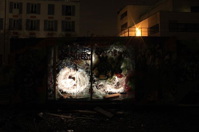 Illuminated graffiti art on a container at night showcases abstract light painting in an urban setting.
