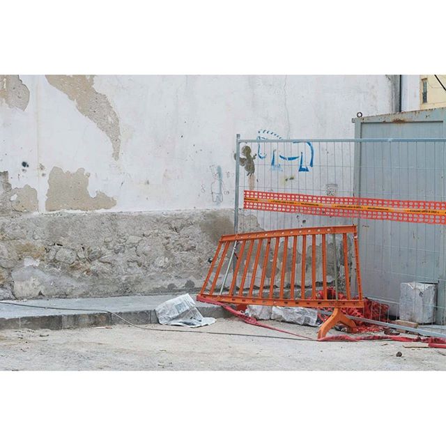 A view of construction barriers and a metal fence on a street.