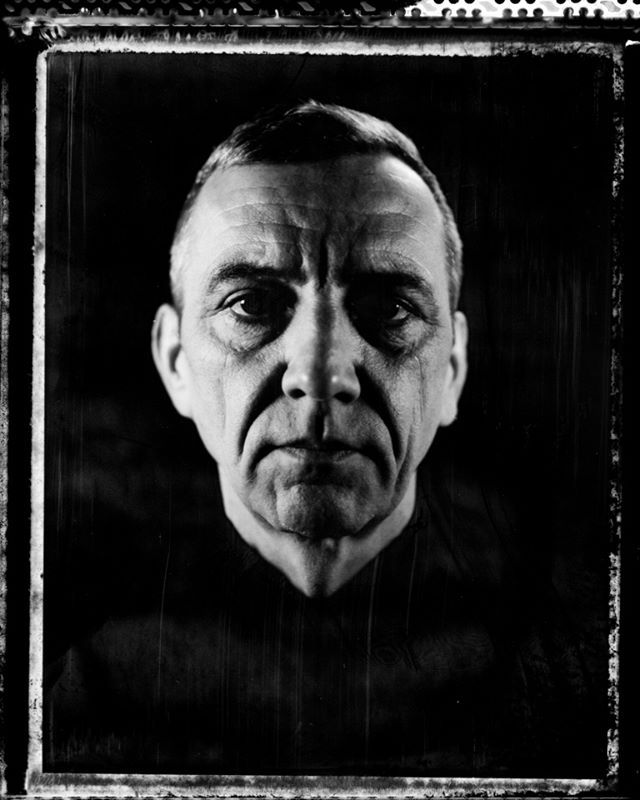 A black and white portrait of a mature man with a serious expression, evoking a sense of experience and contemplation.