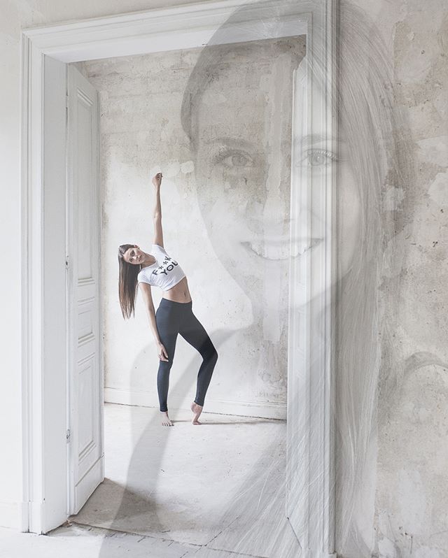 A woman in sportswear strikes a yoga pose in a doorway.