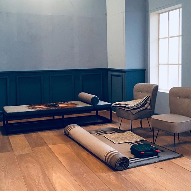 A cozy room setting with furniture and a rolled rug, showcasing a minimalist and modern interior design.