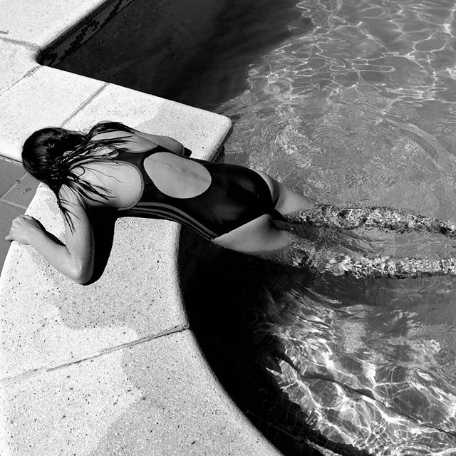 A woman relaxes by the pool, enjoying the water in a black and white composition.