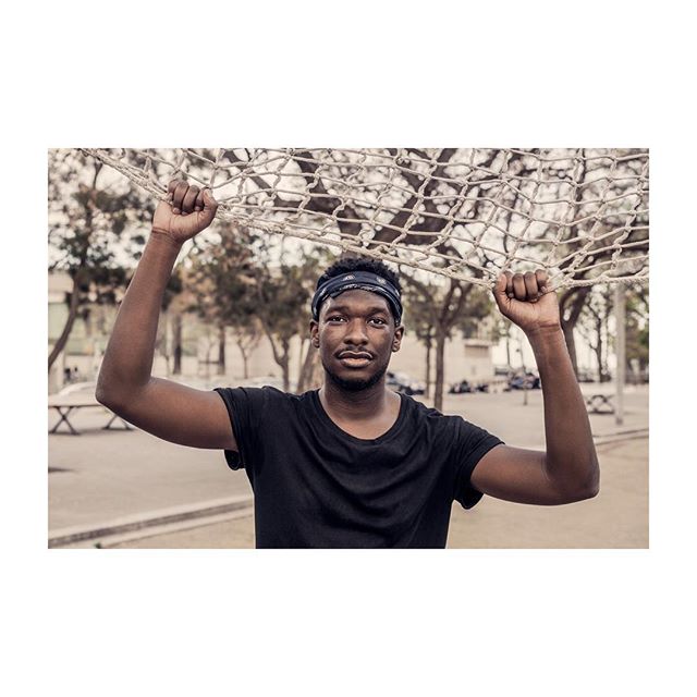 A confident man holds a basketball net in an urban park, perfect for fitness and sports campaigns.