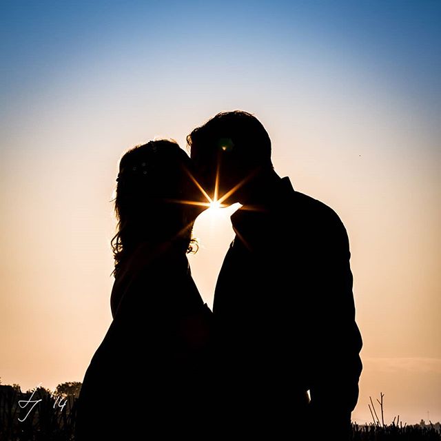 Silhouette of a bride and groom kissing at sunset, symbolizing love and commitment.