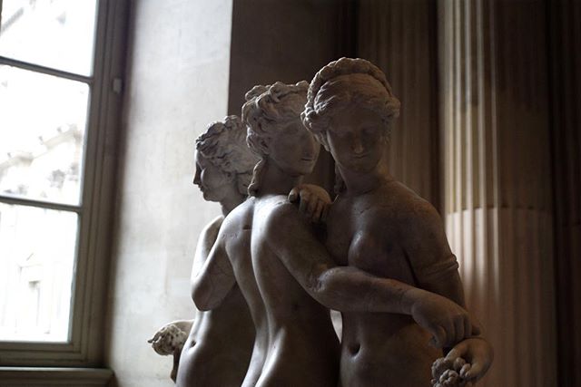 Marble sculpture of the Three Graces in a museum setting.
