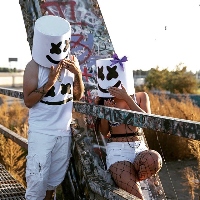 Two people in Marshmallow costumes pose on a bridge, bathed in soft sunlight.