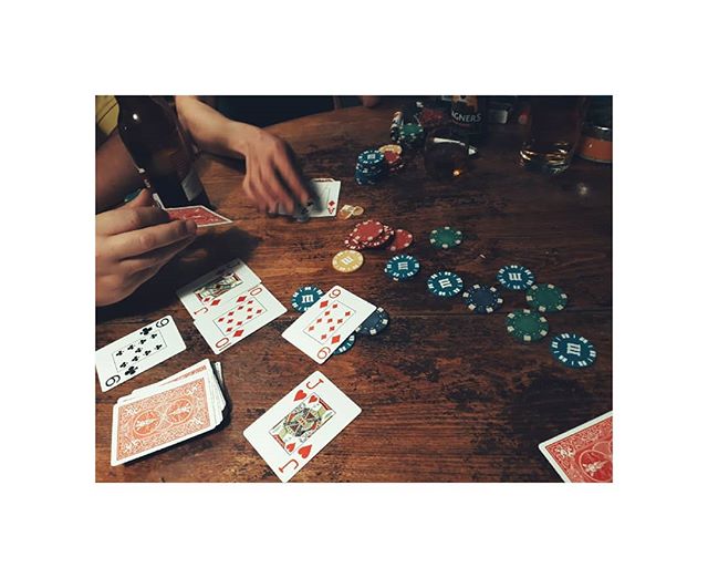 A poker game in progress with cards and chips on a wooden table, capturing a fun and lively social gathering.