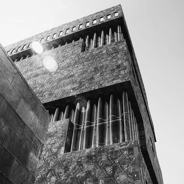 A striking, low-angle shot showcases a modern building with unique architectural details against a bright sky.
