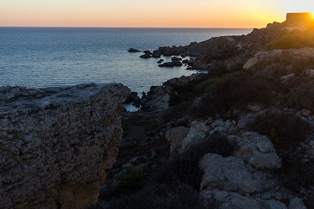 Scenic view of a rocky coastline at sunset, featuring tranquil ocean and natural beauty.
