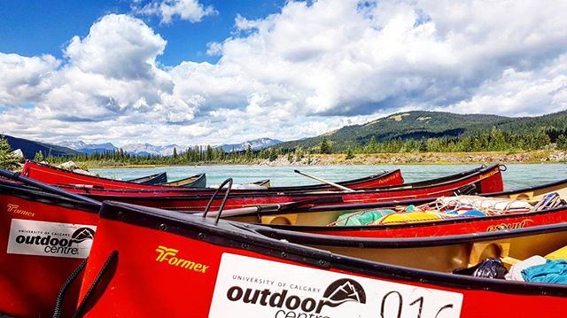 A scenic view of several red canoes on a lake with mountains in the background, perfect for outdoor adventures.