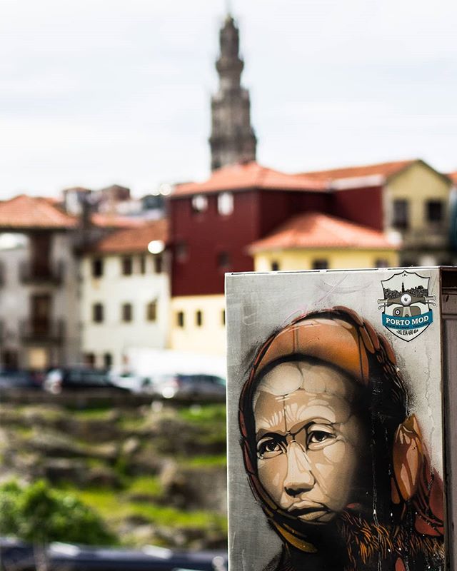 Street art of a woman on a building in a European cityscape. 