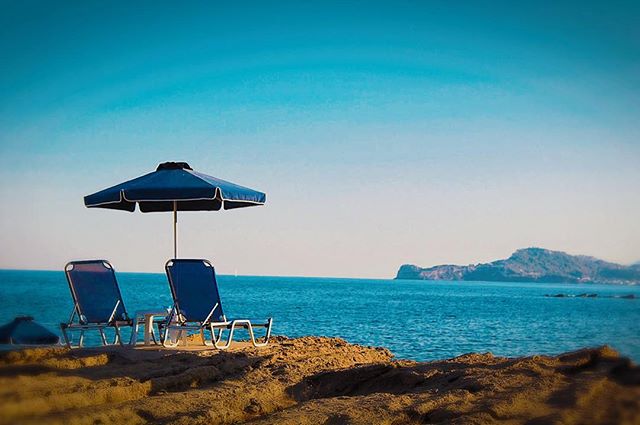 Seascape featuring beach chairs and a sun umbrella on the coast, offering a serene and relaxing vacation scene.