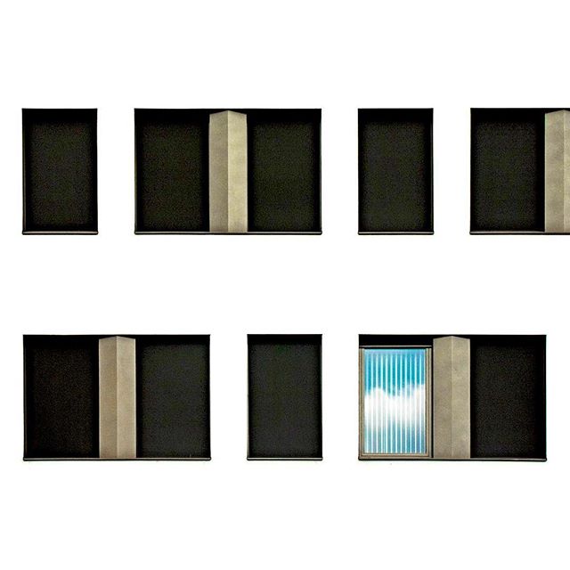 Modern building facade with windows reflecting the sky and clouds, creating a serene urban scene.