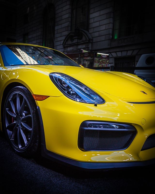 A vibrant yellow Porsche sports car stands out on a city street, showcasing its sleek design.