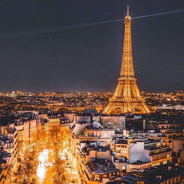The Eiffel Tower and Paris buildings glow at night, creating a captivating cityscape.