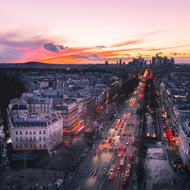 An aerial view shows a vibrant sunset over a busy street and buildings in Paris.