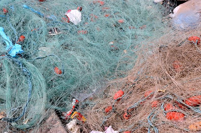 Discarded fishing nets and debris lie tangled, illustrating the impact of waste on the environment and marine life.