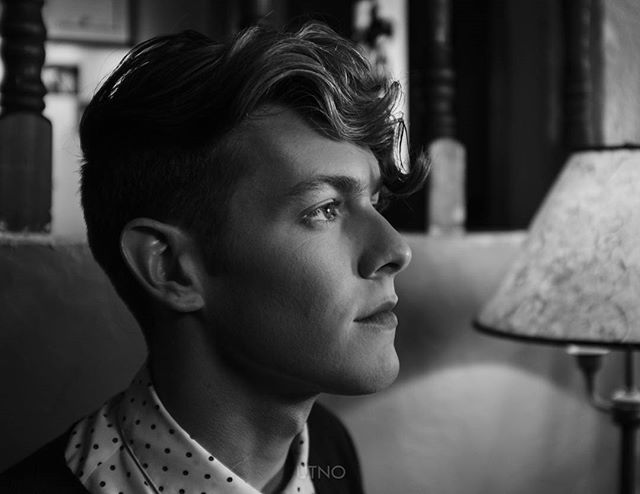 A black and white portrait of a man with stylish hair, looking thoughtful. For editorial or fashion content.