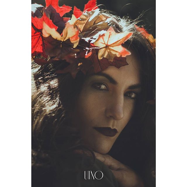 A woman with dark hair and a leaf headdress poses for a moody portrait.