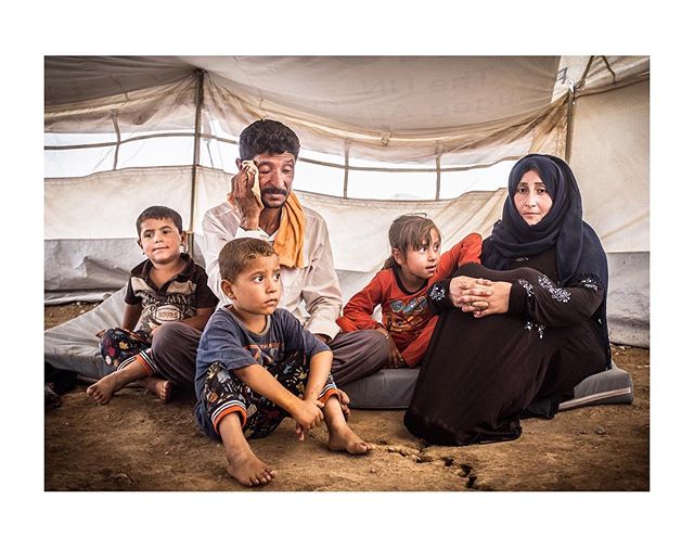 A family of refugees sits in a tent, showing a mix of emotion and hope.