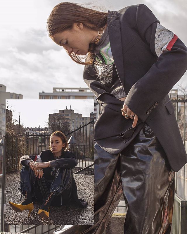 A fashionable woman poses in an urban setting wearing a blazer, sweater and vinyl pants for a fashion editorial.