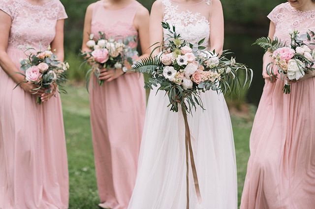Bride and bridesmaids in pink dresses holding bouquets for a romantic outdoor wedding.