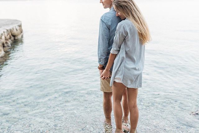 A loving couple stands in the shallow ocean water, holding hands. Focus on love and connection.