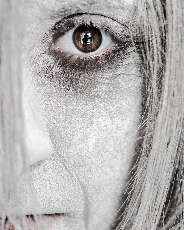 A close-up artistic portrait features a woman's face with a mysterious, intense mood and muted tones.