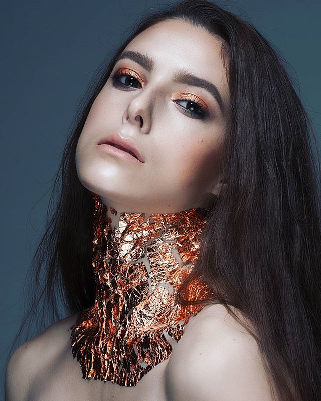 A stunning brunette model with creative metallic makeup showcases editorial beauty and fashion.